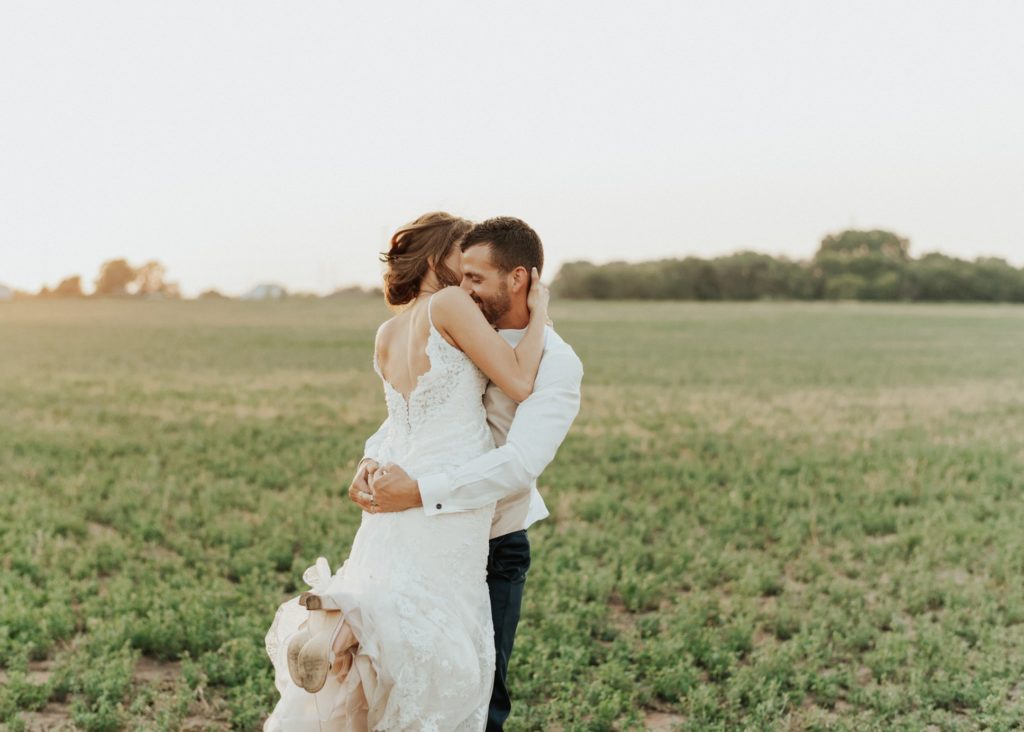 A groom spinning his bride at sunset in a Kansas wheat field.