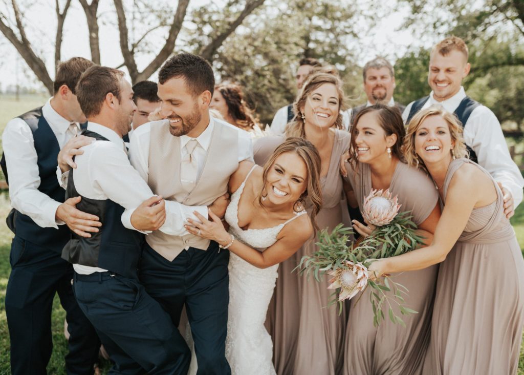 Bridal party hugging the bride and groom at their Colwich, Kansas wedding.