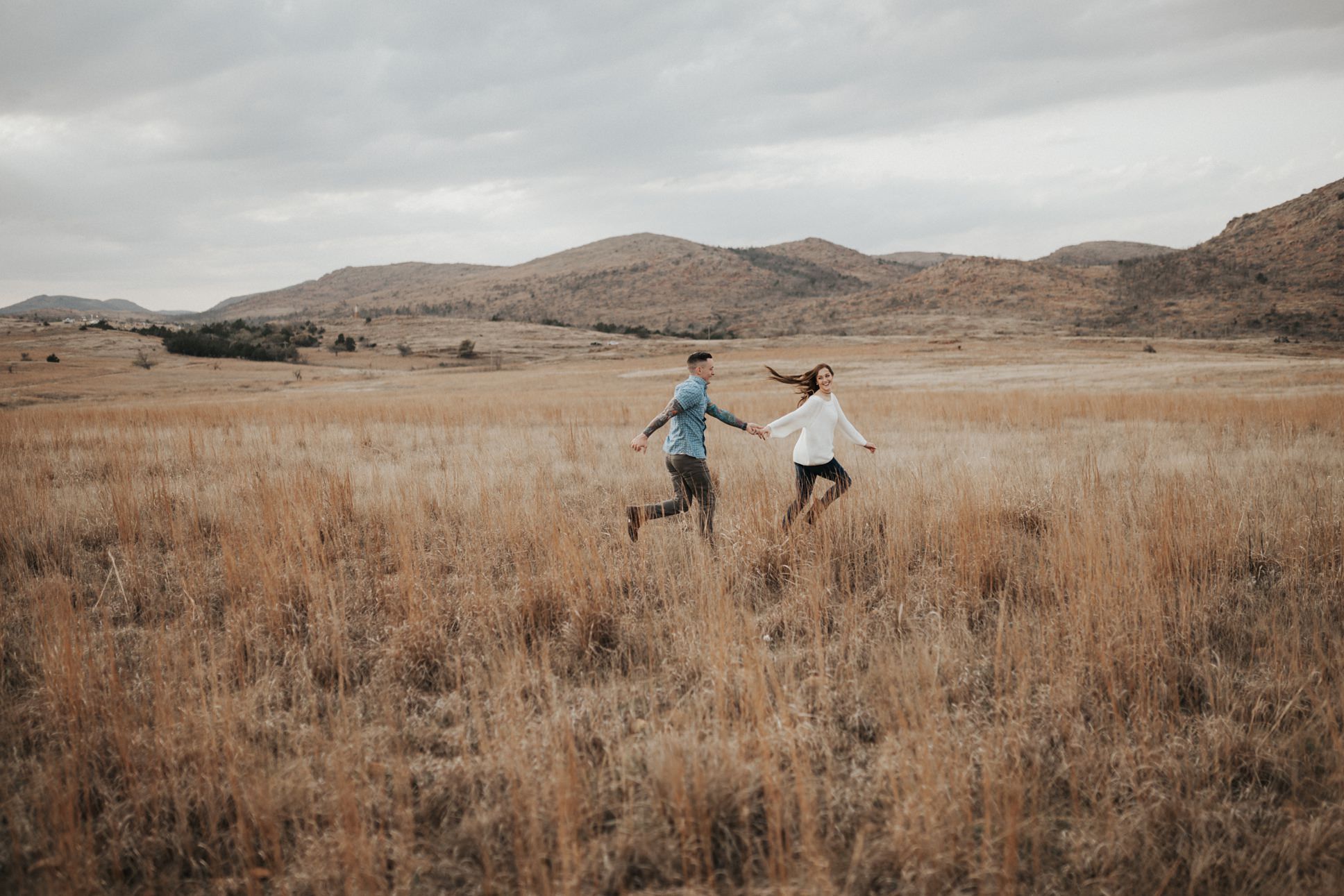 A couple running through a field at their Wichita Mountains engagement session.