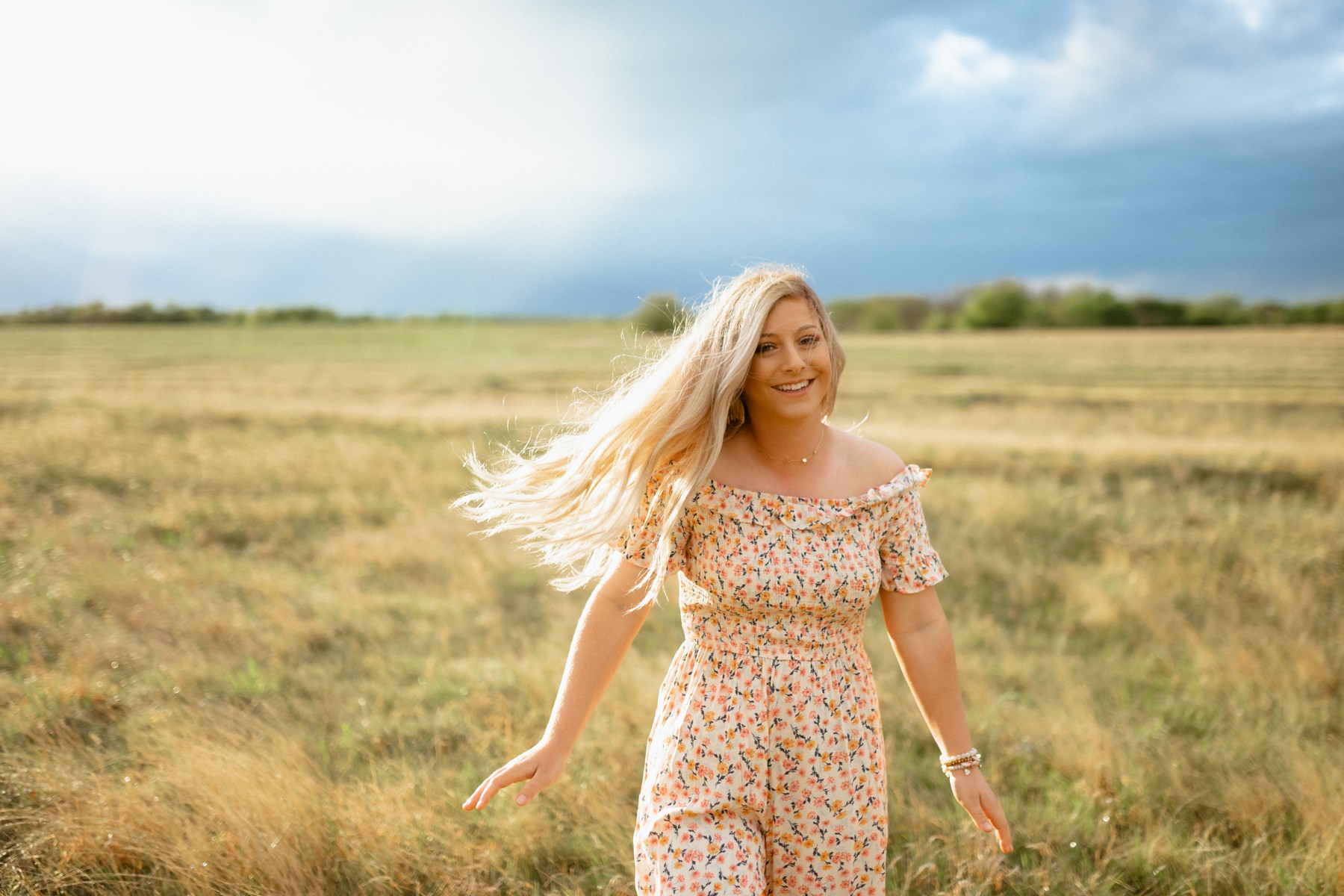 A floral romper in an open field during the spring at her senior photo session.